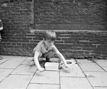 859493 Afbeelding van een kind bij een knikkerpotje in het trottoir van de Pelmolenweg te Utrecht.